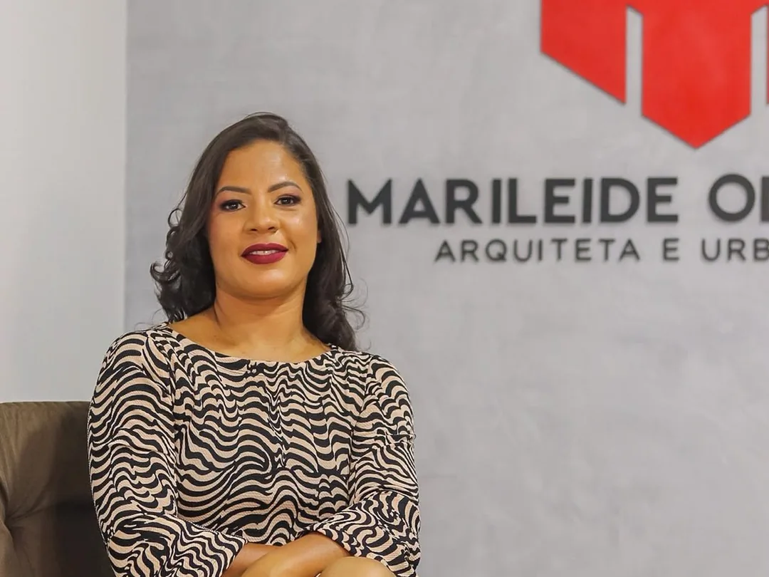 Marileide Oliveira sentada no escritório, com a marca aplicada na parede ao fundo
